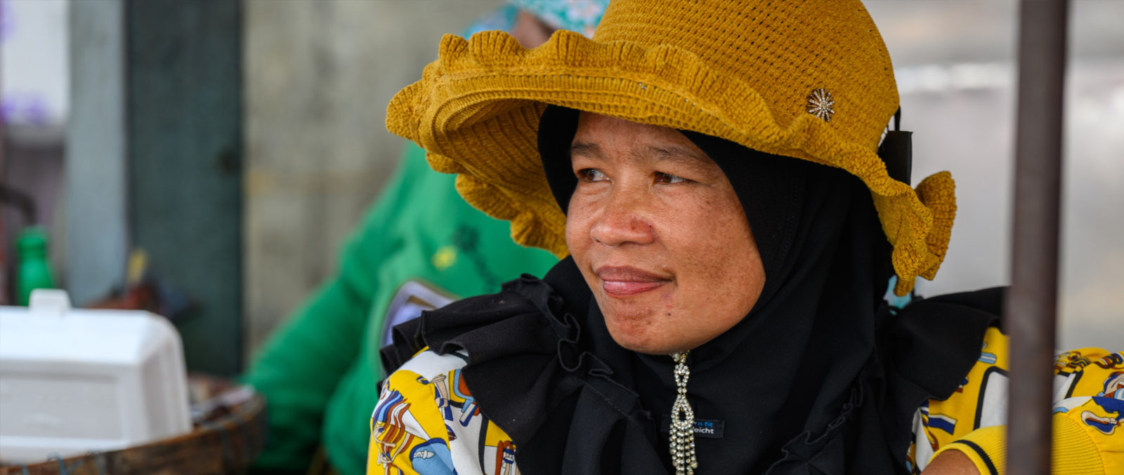 Woman in hat smiling in a market.