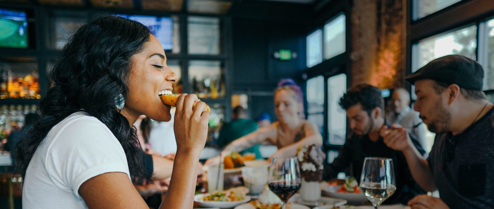 A woman and friends eat happily in a cafe.