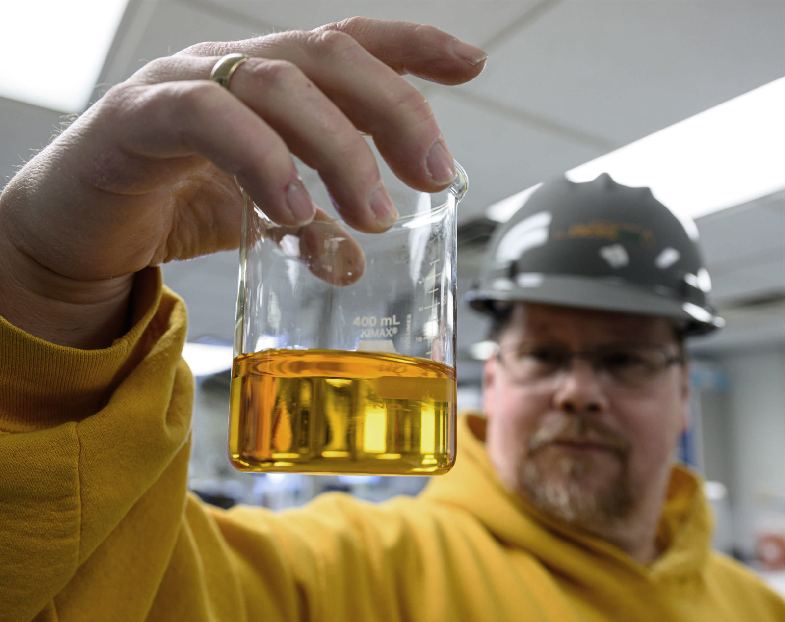 A agricultural engineer holds a glass of soy-based extract.