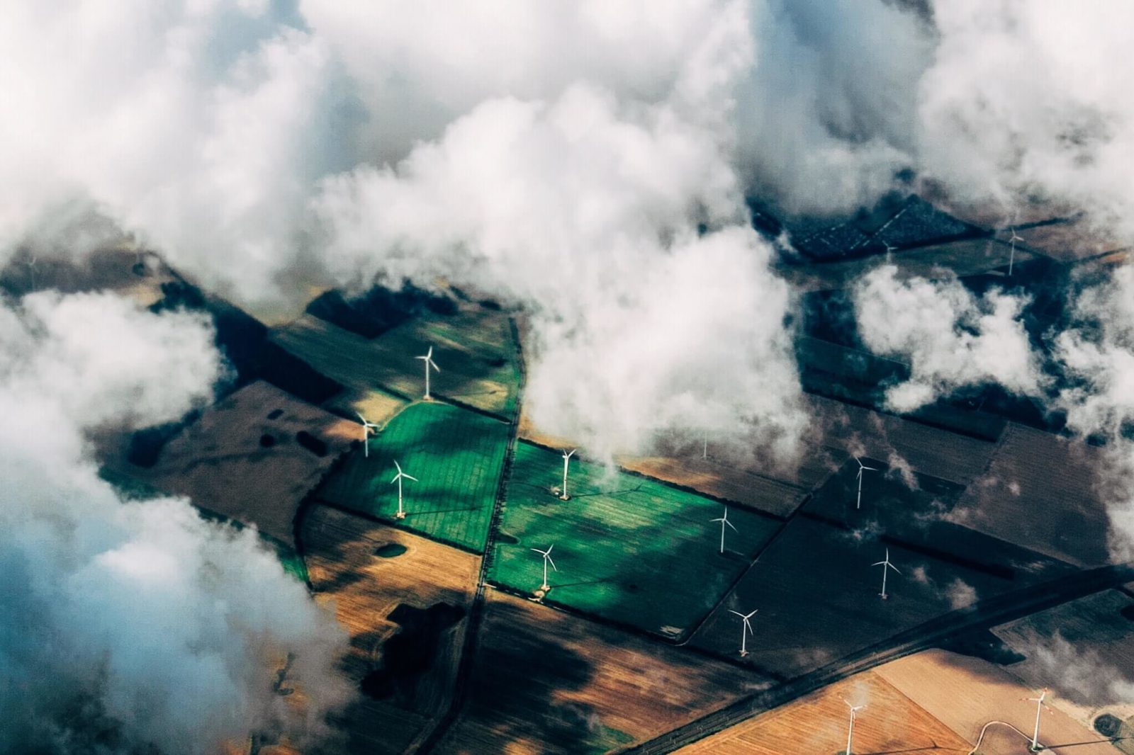 An aerial view of farm fields and wind turbines.